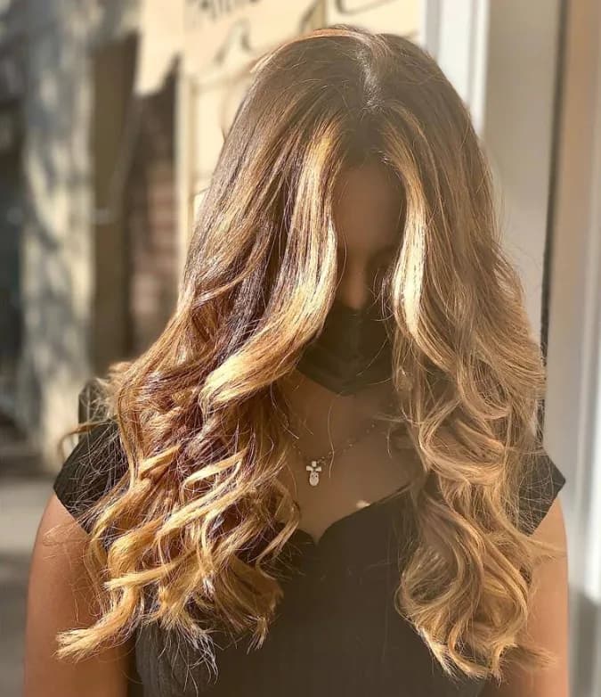 Capelli lunghi con balayage biondo su base castana, onde larghe