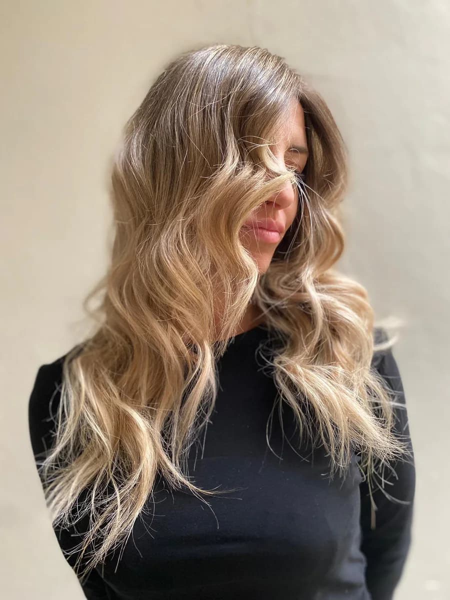 Capelli lunghi con balayage biondo miele e onde morbide, visti di tre quarti