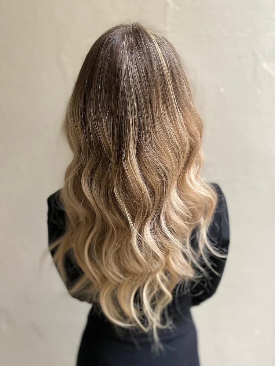 Balayage biondo su base castana, con onde morbide, visto di spalle